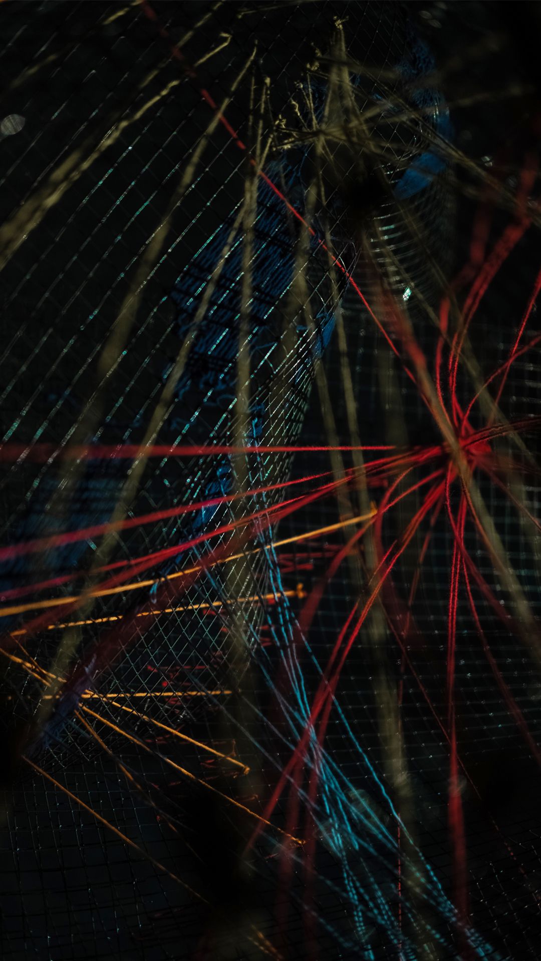 Close-up of the HDDN sculpture where red, orange and blue threads converge across a wire mesh